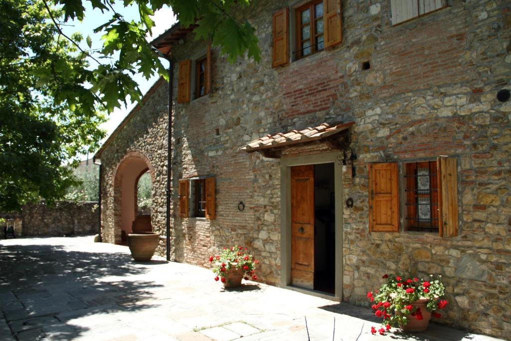 a stone building with a door and flowers in front of it at Podere Fichereto Tuscany apartment in Florence countryside in Scandicci