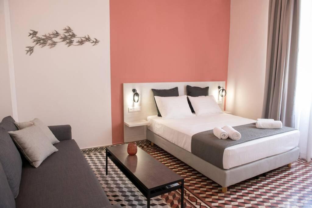 een slaapkamer met een bed en een bank bij Elegant apartment in the heart of Heraklion in Heraklion