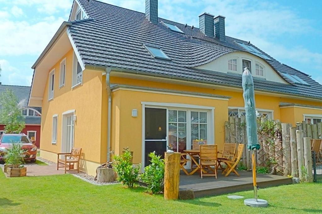 a yellow house with a table and chairs in the yard at Min Hüsken in Zingst