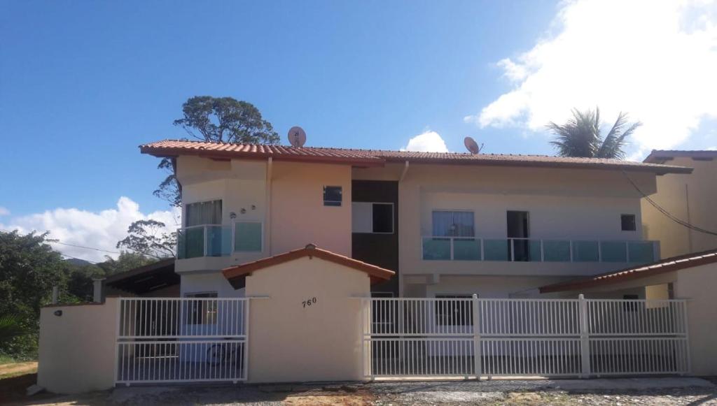 uma casa com uma cerca branca em frente em Chalé Isabela em Ubatuba