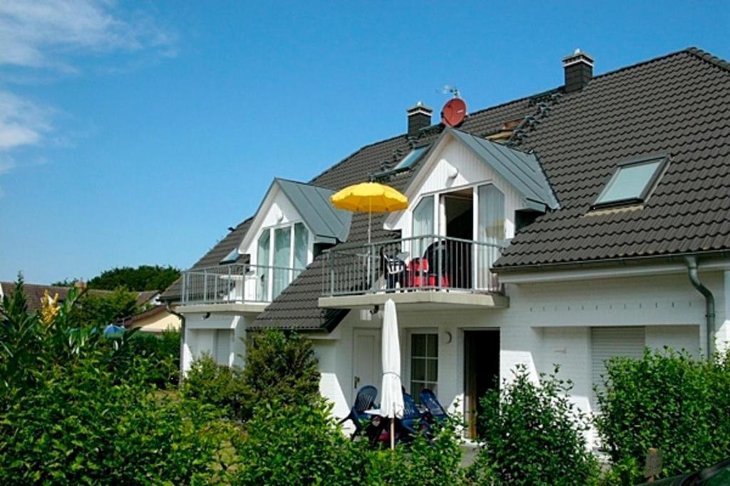 a white house with a yellow umbrella on the balcony at Am Strand 4,PP innen in Zingst