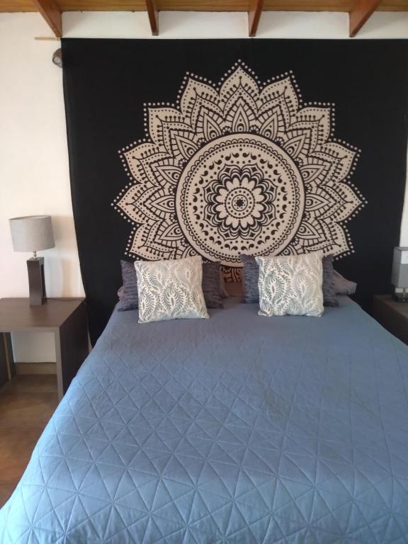 a bedroom with a blue bed with a mandala headboard at Posada Soleil Bed & Breakfast in Valle de Guadalupe