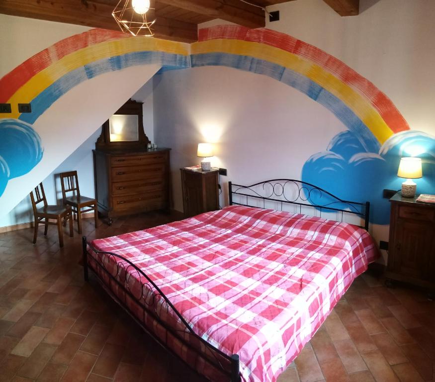 um quarto com uma cama com um arco-íris pintado na parede em La Casa di nonna Adri - Casa vacanze in Casentino em Stia
