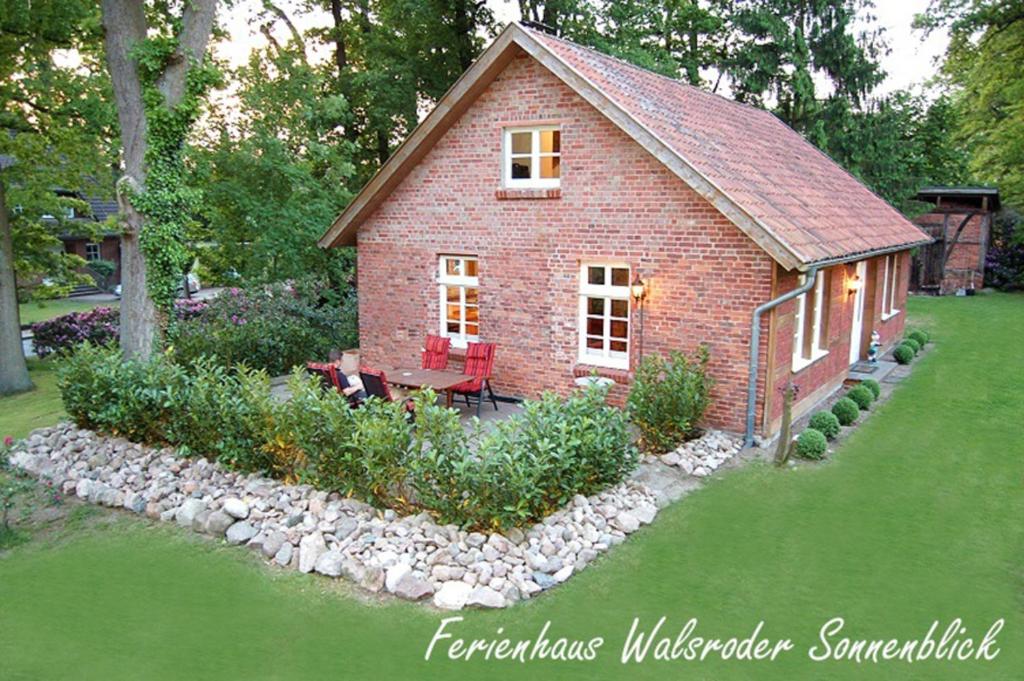 a small red brick house with a garden in the yard at Ferienhaus Sonnenblick - a59190 in Walsrode