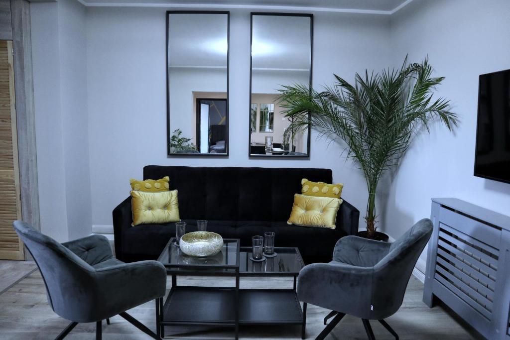 a living room with a black couch and chairs at Apartament Royal in Dej