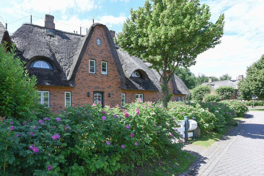 ein altes Backsteinhaus mit Blumen davor in der Unterkunft August-Endell-Weg 3 in Südstrand