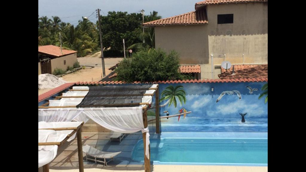 a swimming pool with a mural on the side of a building at Casa Temporada Frente à Praia Piscina Ar cond Nova Viçosa VA in Nova Viçosa