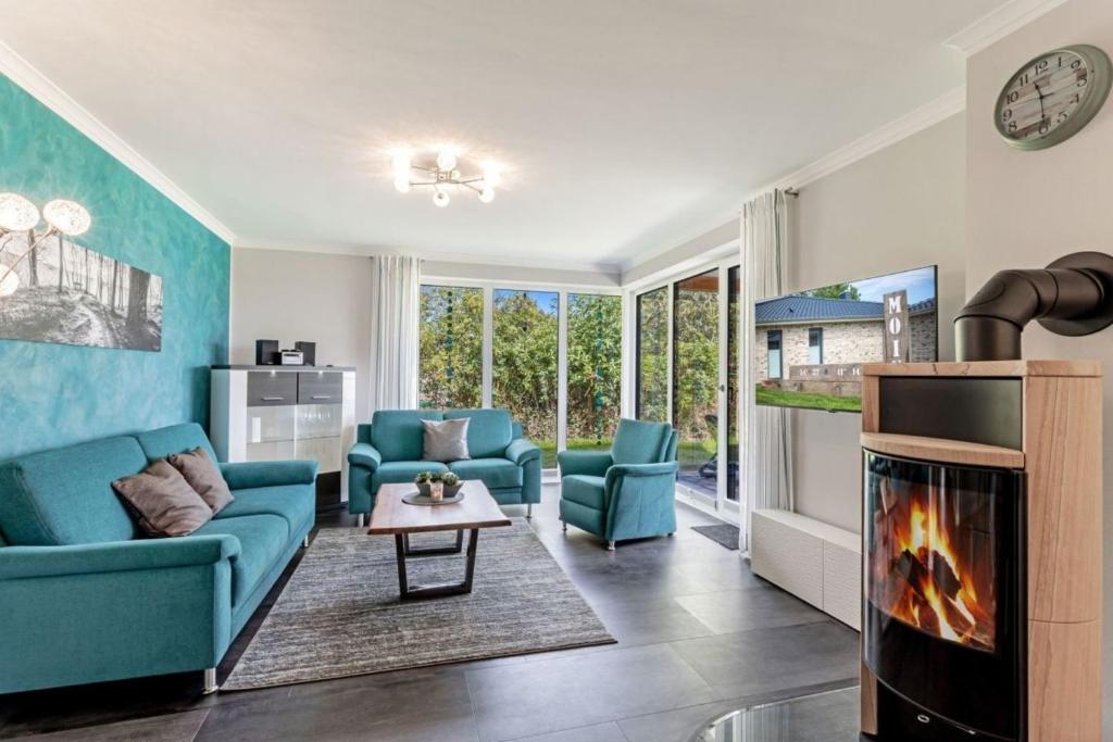 a living room with blue furniture and a fireplace at Relax Bungalow Strandperle in Klausdorf