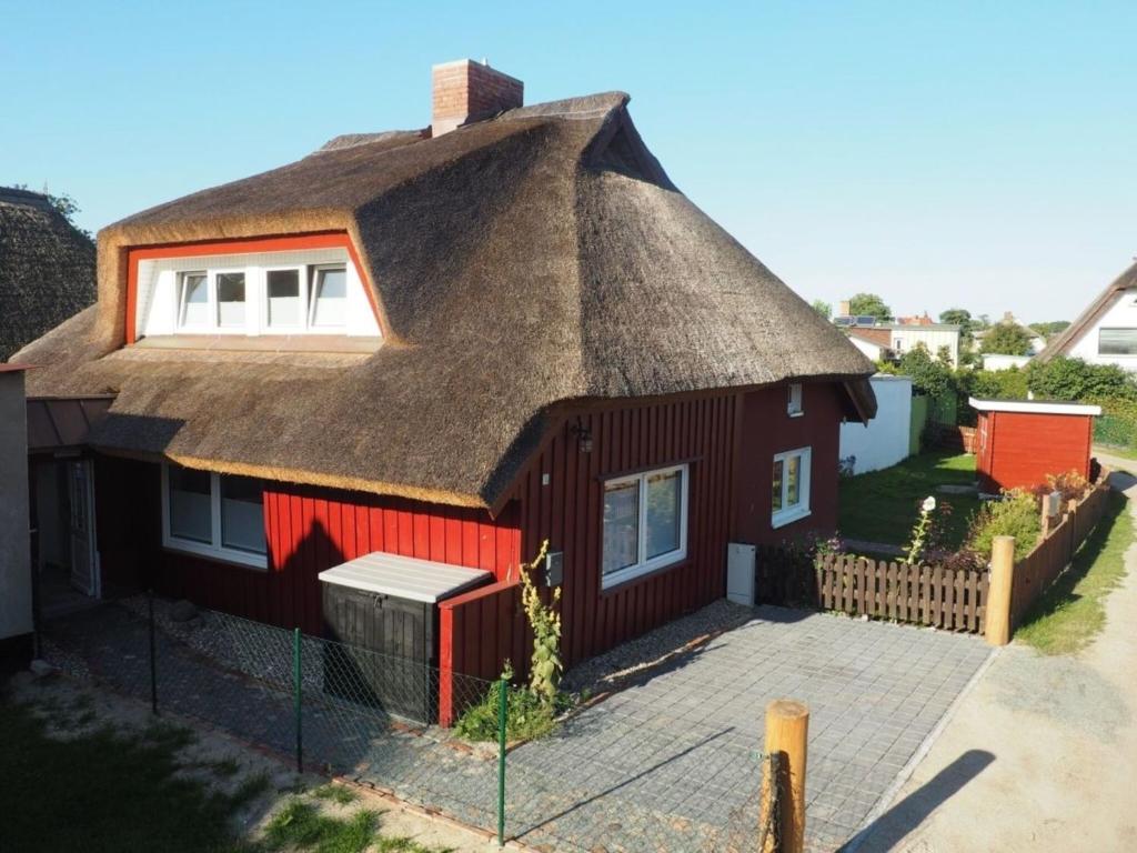 una pequeña casa roja con techo de paja en Dwargenhus, en Prerow