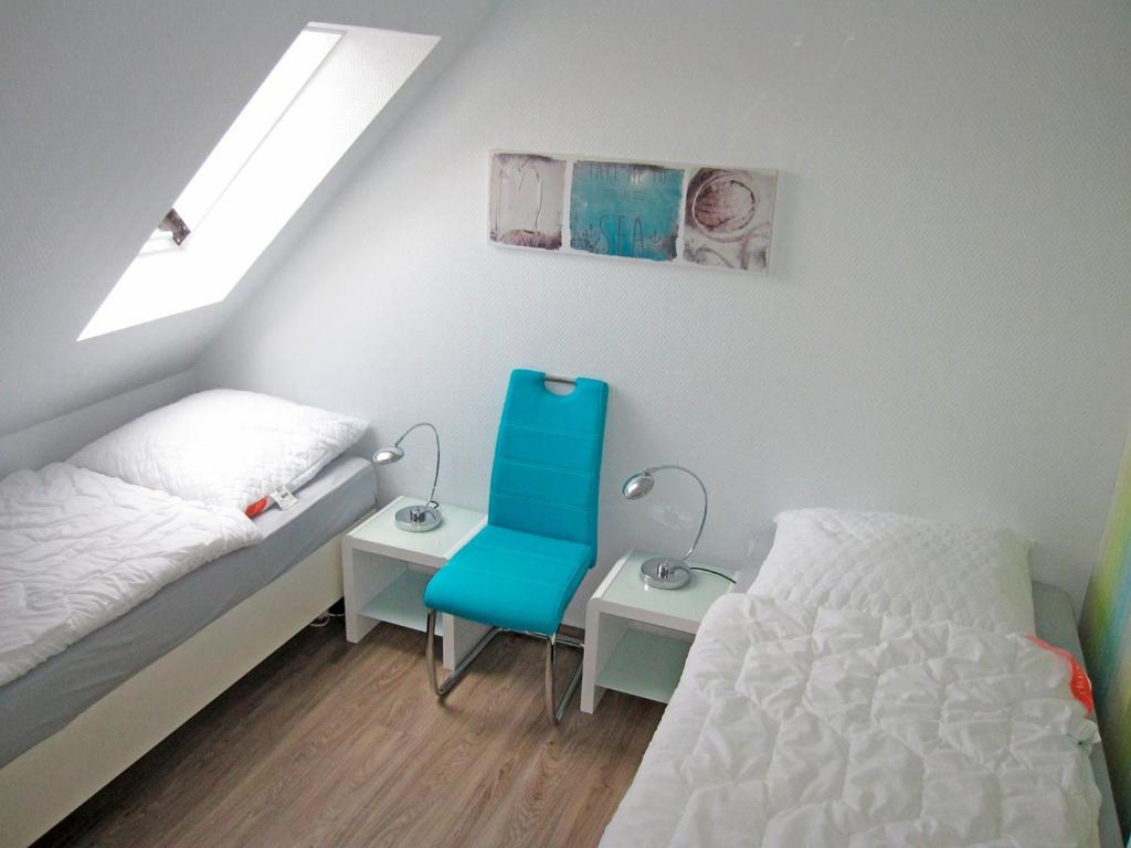 a bedroom with a bed and a blue chair at "Landhaus Voss" Typ 4 Nr11 in Staberdorf
