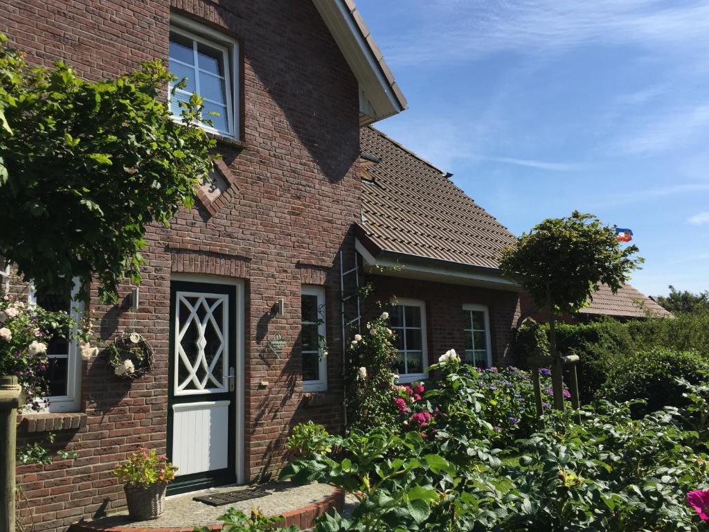 a brick house with flowers in the front yard at Nordwind in Oevenum