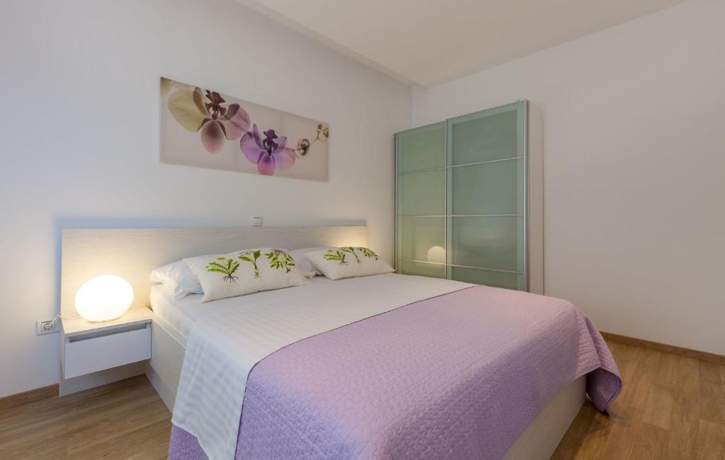 um quarto branco com uma grande cama com lençóis roxos em Azalea A1 em Podstrana