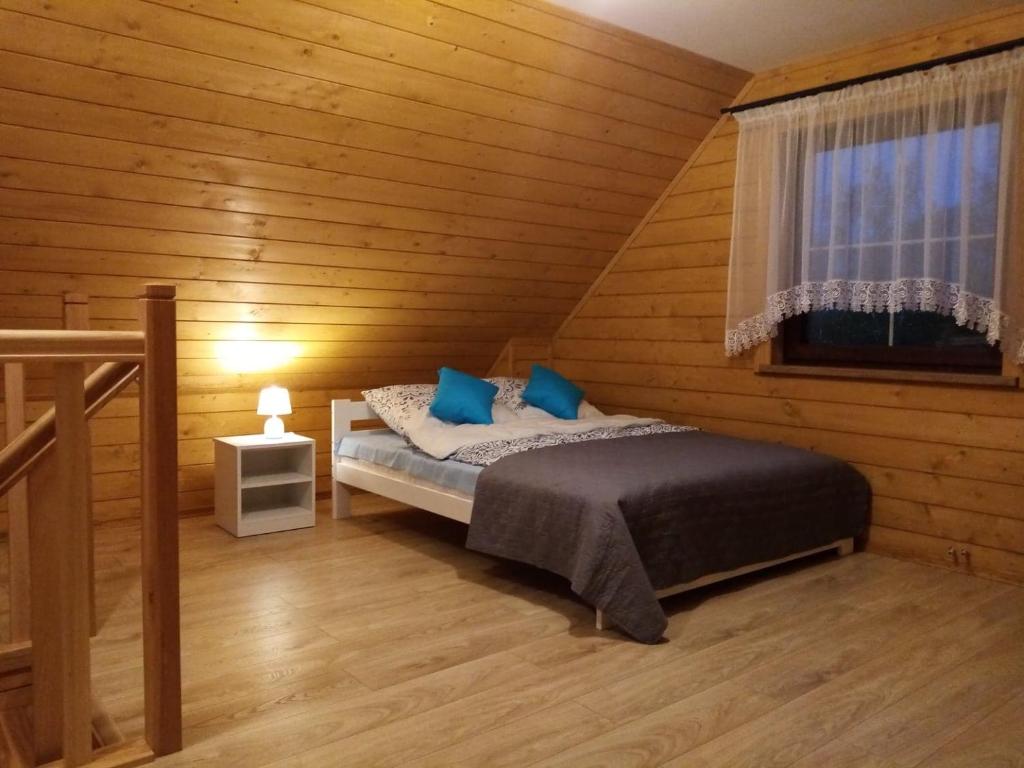 Un dormitorio con una cama con almohadas azules y una ventana en Siedlisko Czarny Dzięcioł, en Narewka