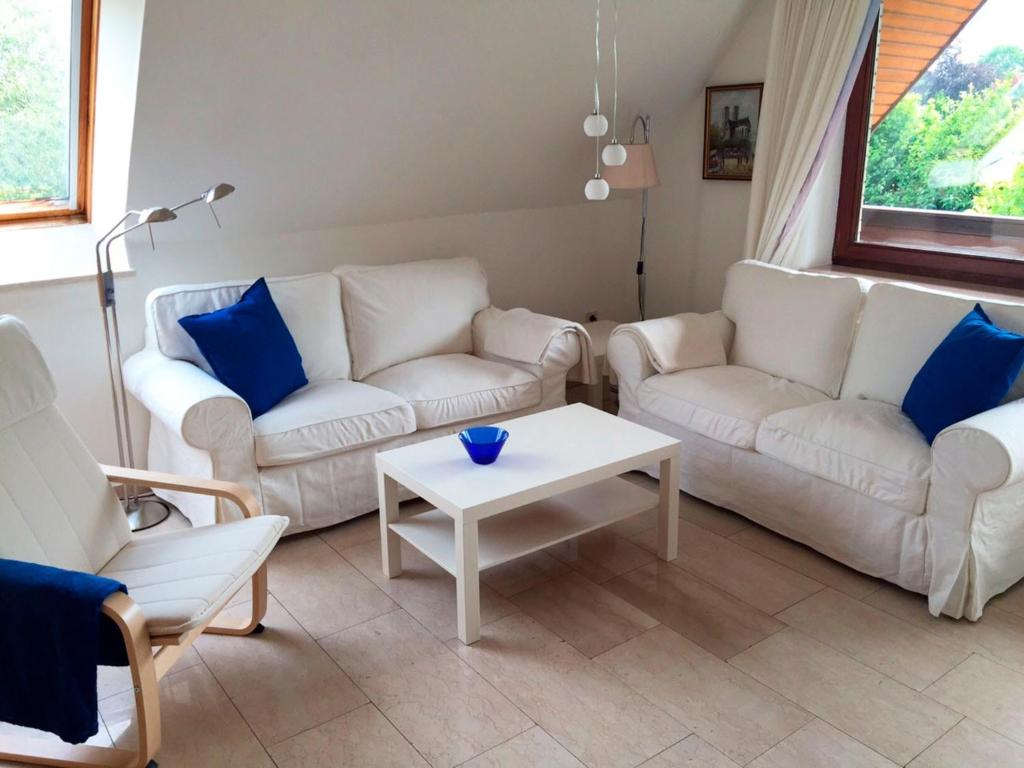 a living room with two white couches and a table at FeWo Gottorf in Ulsnis