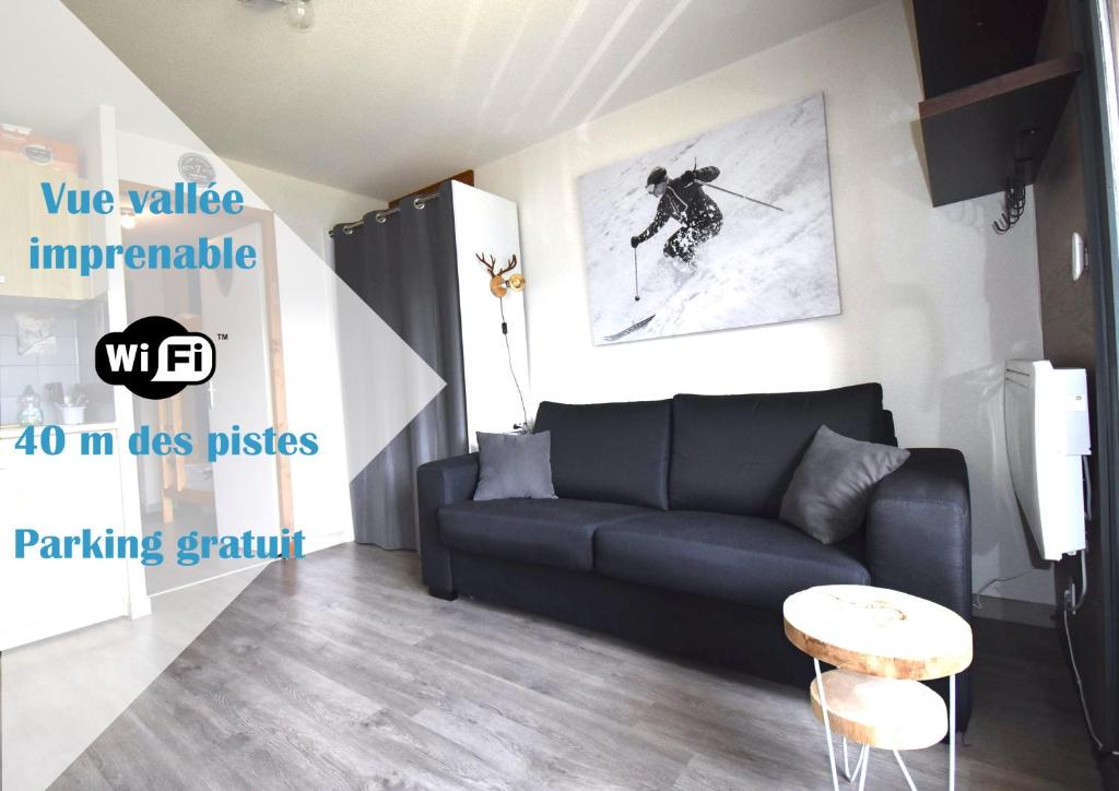 un salon avec un canapé et une photo de skieur dans l'établissement Au Pied des Pistes B31, Chaleureux studio 4 pers, vue sur la vallée imprenable avec WIFI, DRAPS NON COMPRIS, à Saint-Jean-dʼAulps