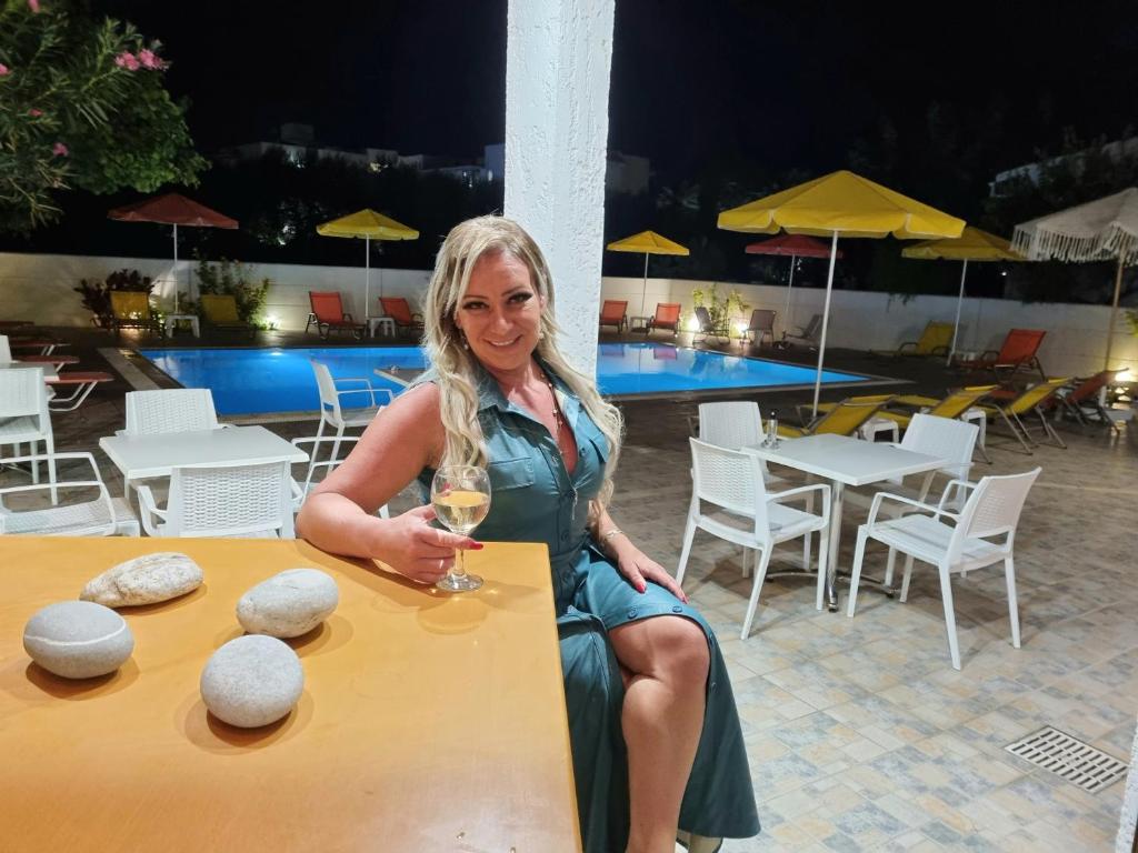 een vrouw aan een tafel met een glas wijn bij Arhodiko Hotel in Amoudara Herakliou