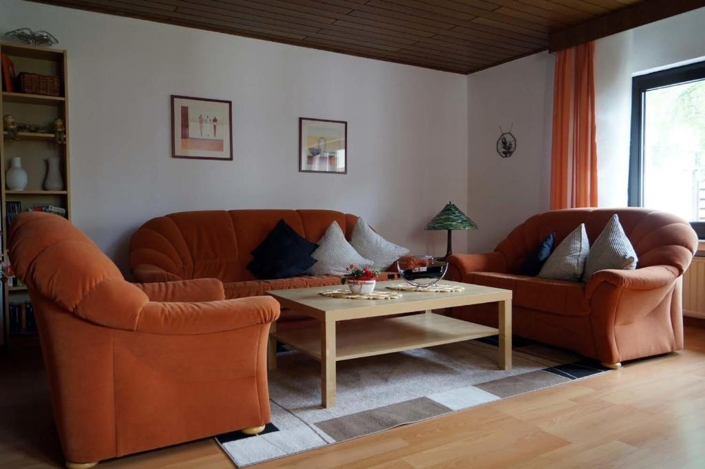 uma sala de estar com dois sofás laranja e uma mesa em Eifelferienhaus Thome em Lissendorf