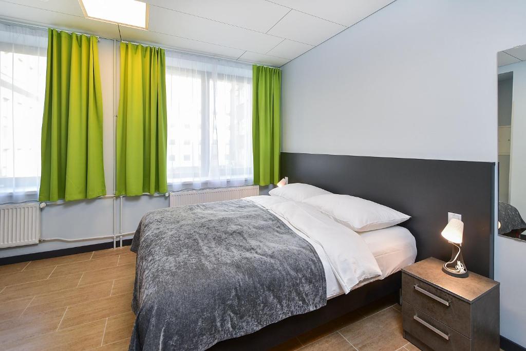 a bedroom with a large bed with green curtains at City Yard Inn Hotel in Tallinn