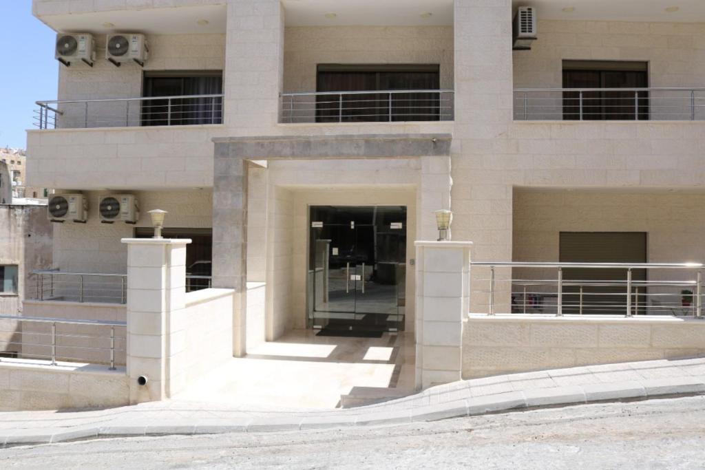 Großes weißes Gebäude mit Balkon in der Unterkunft Amazing one Bedroom Apartment in Amman Elwebdah 7 in Amman