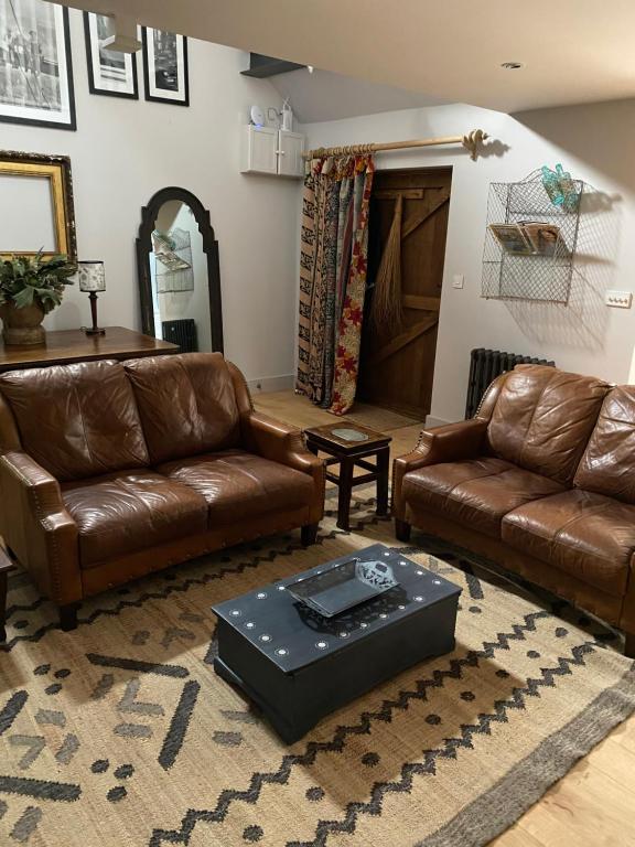 a living room with two leather couches and a table at Holly Cottage The Studio in Hinstock