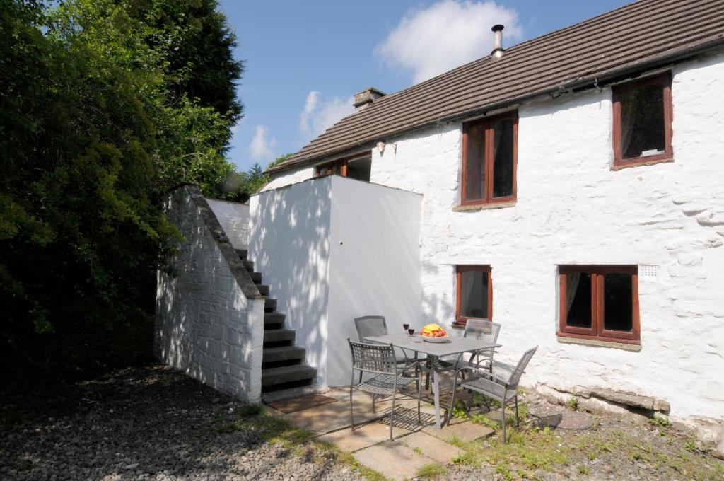 una mesa y sillas frente a una casa blanca en Ghyll Burn Cottage and Barn End Cottage, en Alston