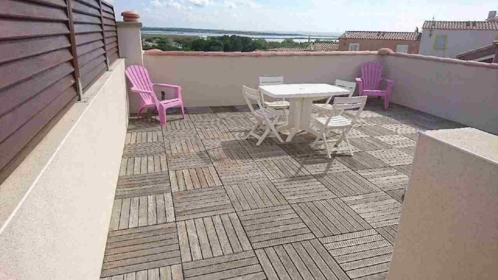 un patio con mesa y sillas en la azotea en les terrasses de la mer, en Saint Pierre La Mer