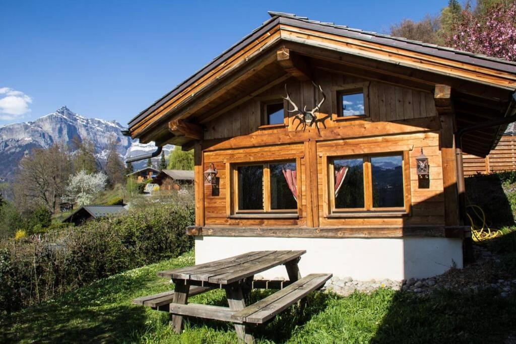 una cabaña de madera con un banco de picnic frente a ella en Chalet cosy proche Tramway du Mont-Blanc et centre, en Saint-Gervais-les-Bains