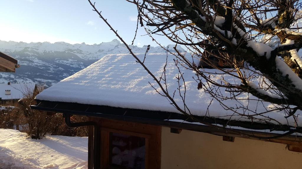 a snow covered roof of a house with mountains in the background at Chalet cosy proche Tramway du Mont-Blanc et centre in Saint-Gervais-les-Bains