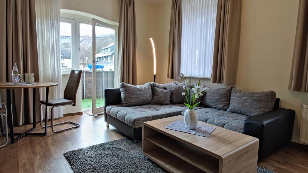 uma sala de estar com um sofá e uma mesa em Ferienwohnung Viaduktblick mit Balkon & MeineCardPLUS em Willingen