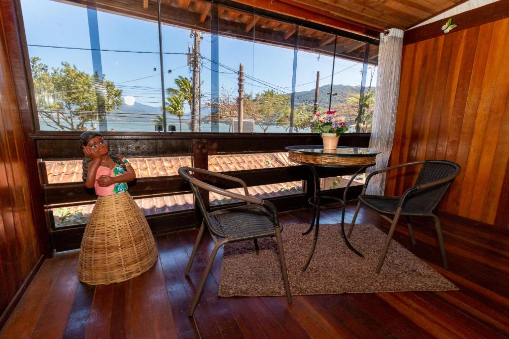 a woman standing in a room with a table and chairs at Pousada Casa da Praia in Mangaratiba