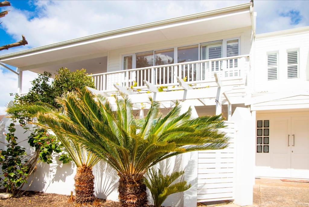 a white house with palm trees in front of it at Beach House 11B in Groot Brak Rivier