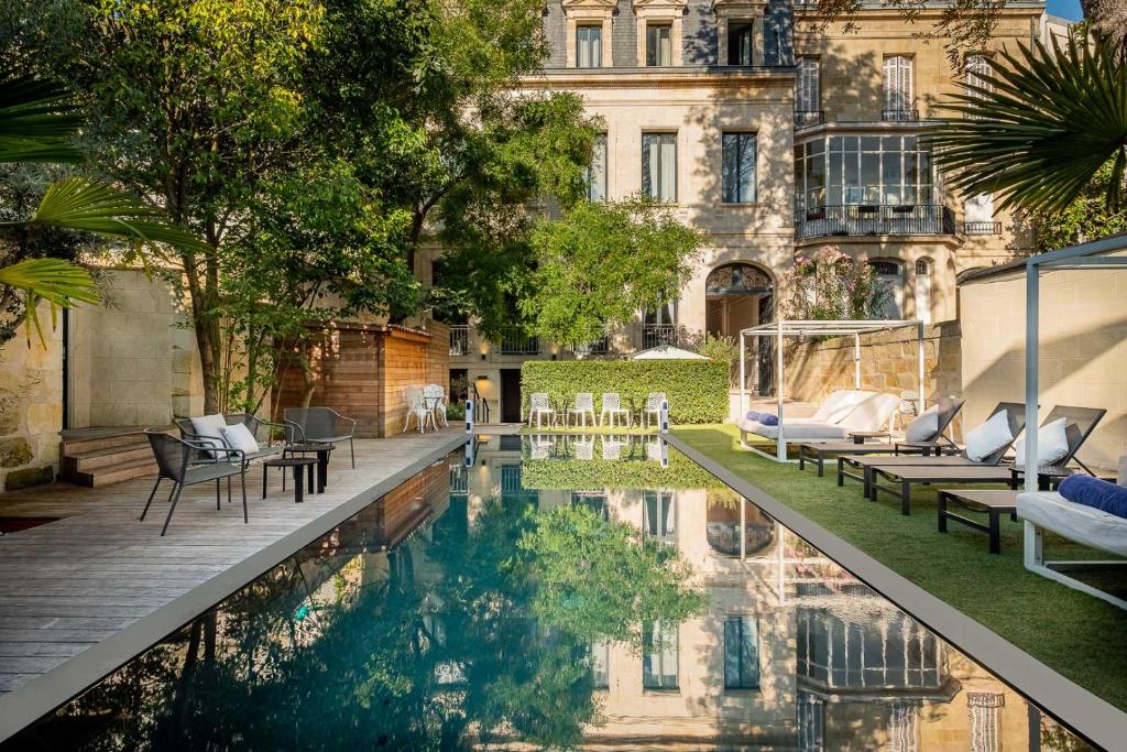 a patio area with a pool, chairs, and tables at Le Palais Gallien Hôtel & Spa in Bordeaux