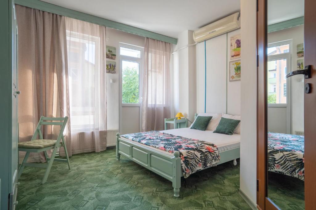 ein Schlafzimmer mit einem Bett, einem Stuhl und einem Fenster in der Unterkunft Къща за гости Арт Хаус - Юг/ Art House - South in Sandanski