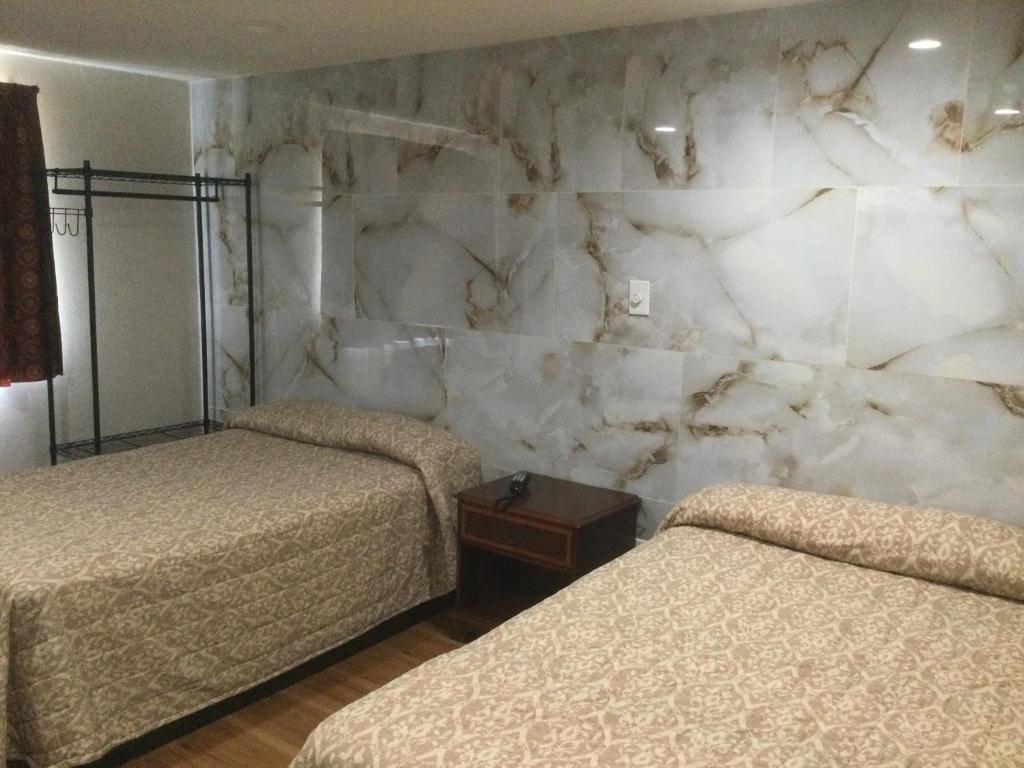 1 dormitorio con 2 camas y pared de piedra en Americas Express Inn Rocky Mount, en Rocky Mount