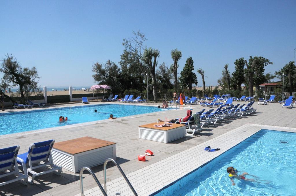 a pool with chairs and people in the water at Campeggio Falconera in Caorle