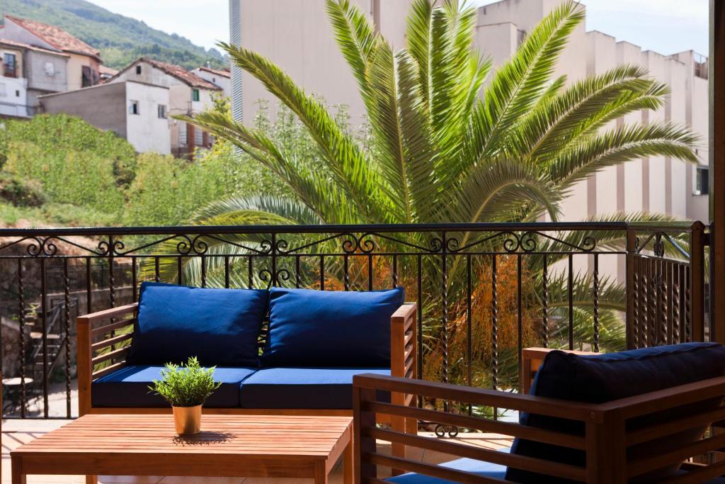 a blue couch on a balcony with a palm tree at Hotel Rural El Molino in Baños de Montemayor