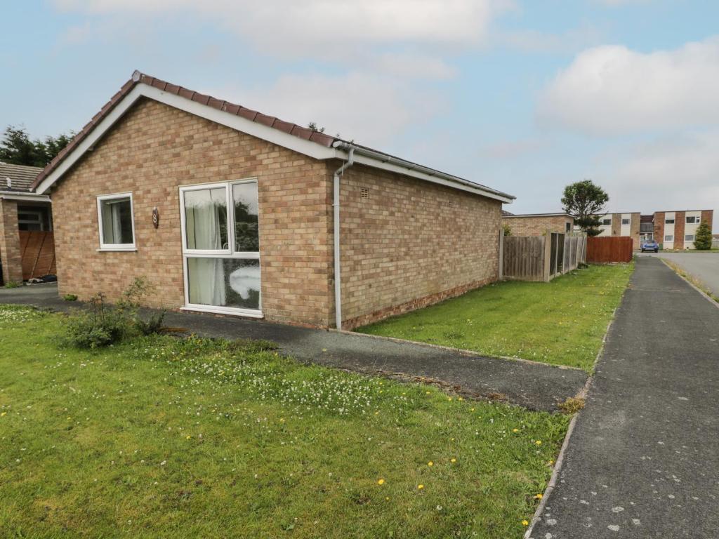 a brick house with a grass yard in front of it at 8 Dysynni Walk in Tywyn