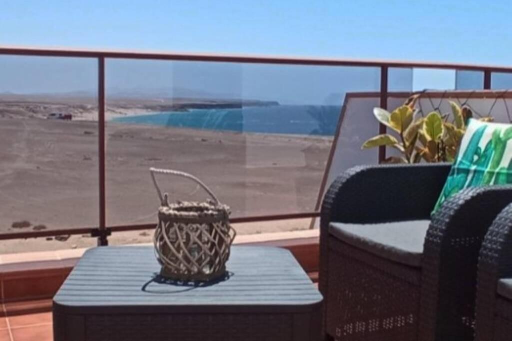 a table and a chair on a balcony with a view at Casa Las Olas in Cotillo