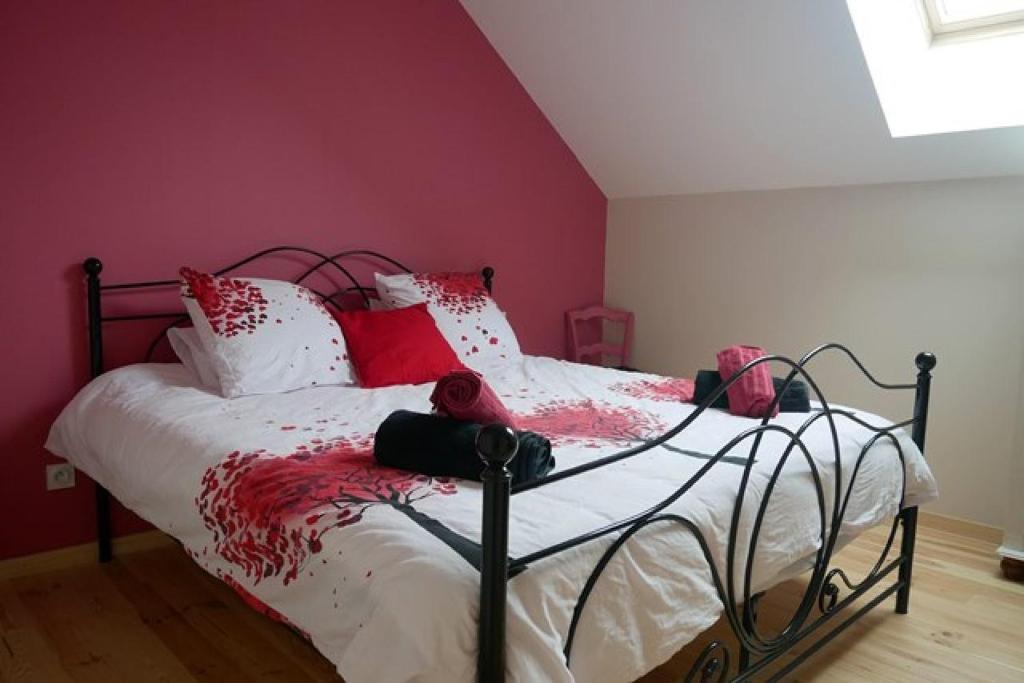 chambre d hôte La Grange في Pommiers-en-Forez: غرفة نوم بسرير ومخدات حمراء وبيضاء