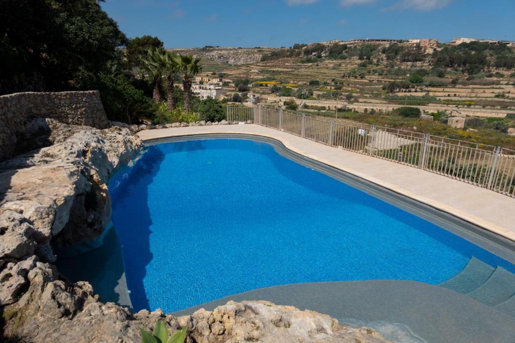 a swimming pool with blue water and a mountain at Villeleynah Holiday Home in Munxar