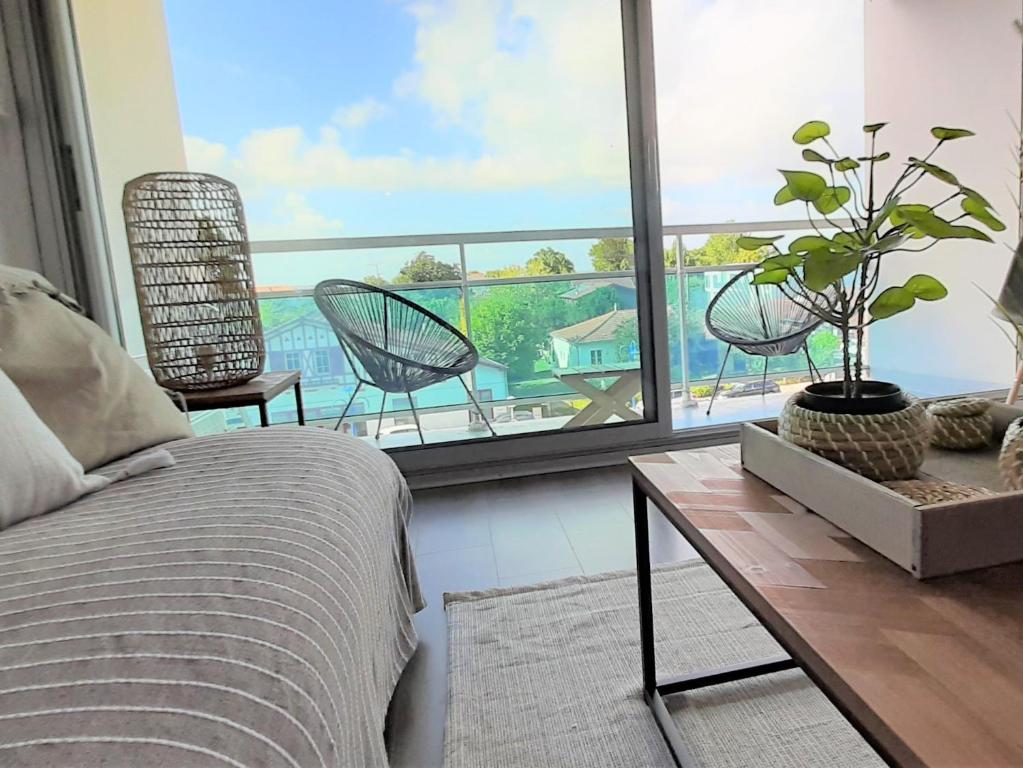 a bedroom with a bed and a balcony with chairs at Résidence Estey T2 centre avec aperçu Bassin in Andernos-les-Bains