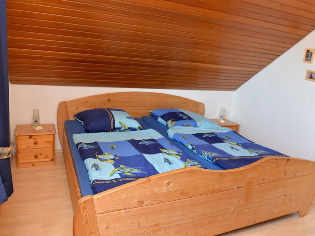 Schlafzimmer mit einem Holzbett mit blauer Decke in der Unterkunft Fewo 91 WHG C 21 in Burhave in Burhave