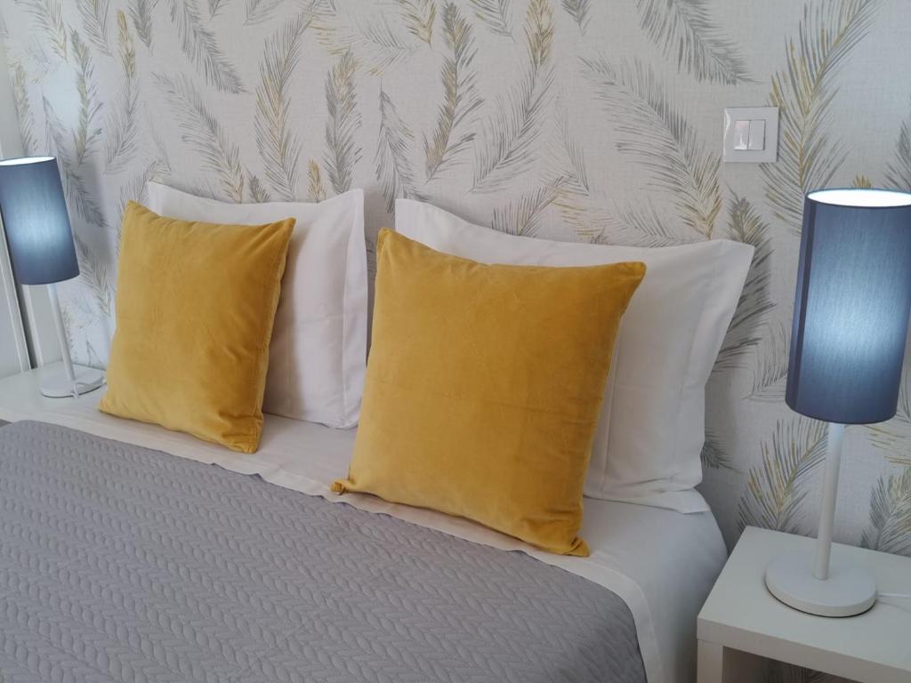 a bed with white pillows and yellow pillows at Palmeira Comfort in Aveiro