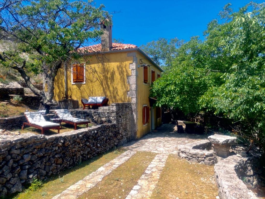 a yellow house with a stone wall and a patio at Melina Heritage House in Cres