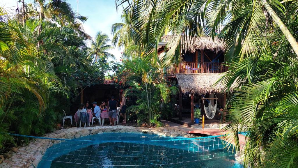 a resort with a swimming pool and palm trees at Tower Bridge Hostel in Puerto Escondido