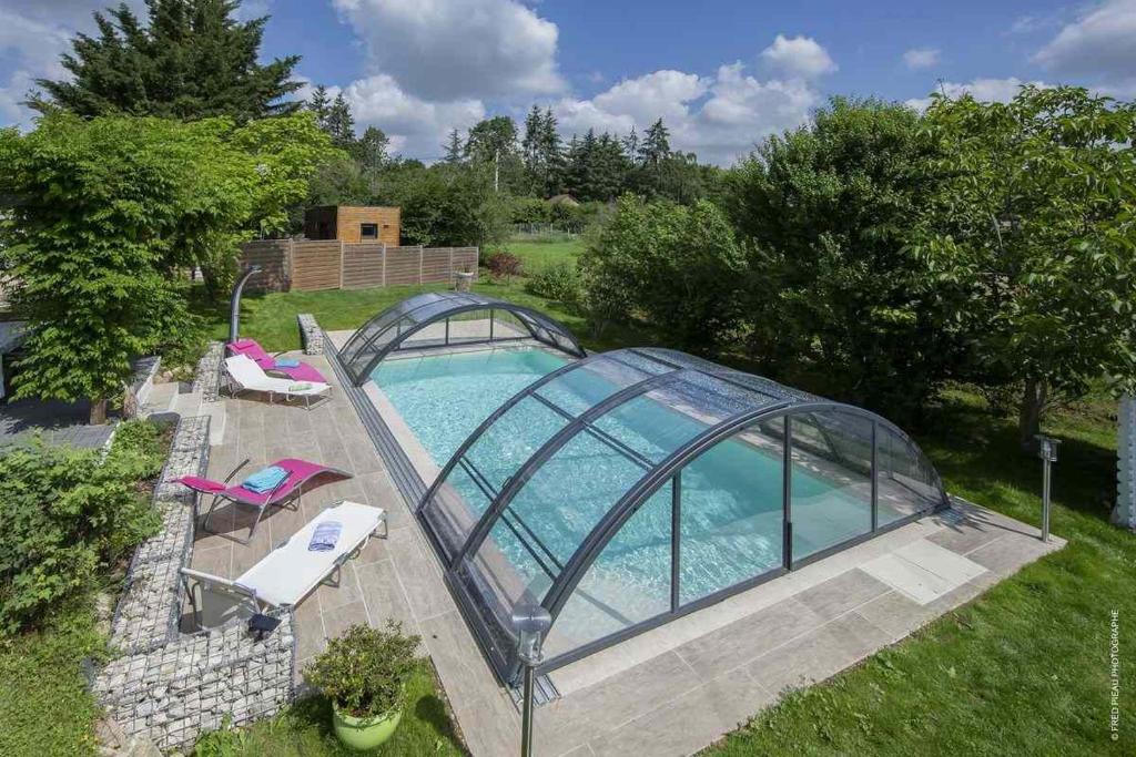 une piscine entourée d'une serre en verre. dans l'établissement Au Coeur Du Bien Etre, chambre d'hôtes avec piscine chauffée et couverte, SPA, sauna, massages, à Monteaux