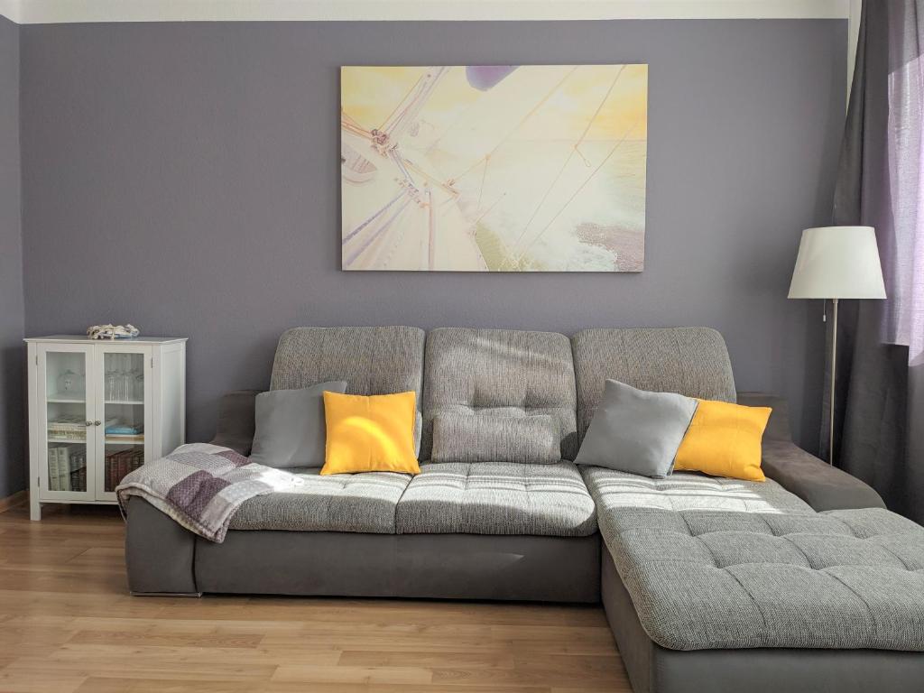 ein Wohnzimmer mit einem grauen Sofa und gelben Kissen in der Unterkunft Seerose in Görlitz