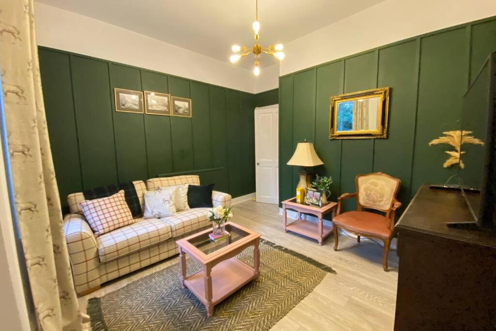 uma sala de estar com paredes verdes, um sofá e uma mesa em Old City Gem Flat em Aberdeen