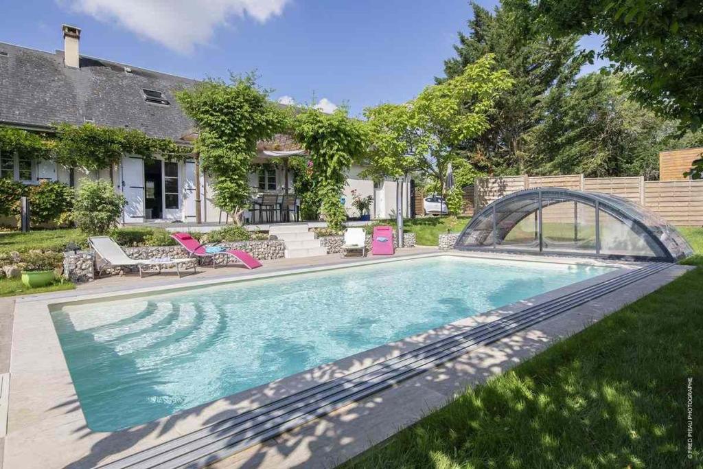 a swimming pool in the yard of a house at Au Coeur du Bien-Etre, gîte avec piscine chauffée et couverte, SPA, sauna, massages in Monteaux