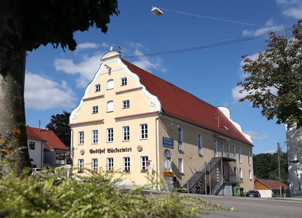 een groot wit gebouw met een rood dak bij Backerwirt - Wohnen und Schlafen in Welden